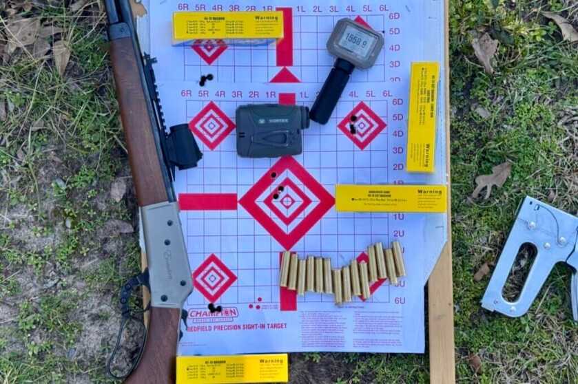 Paper target with ammo, rangefinder, and rifle