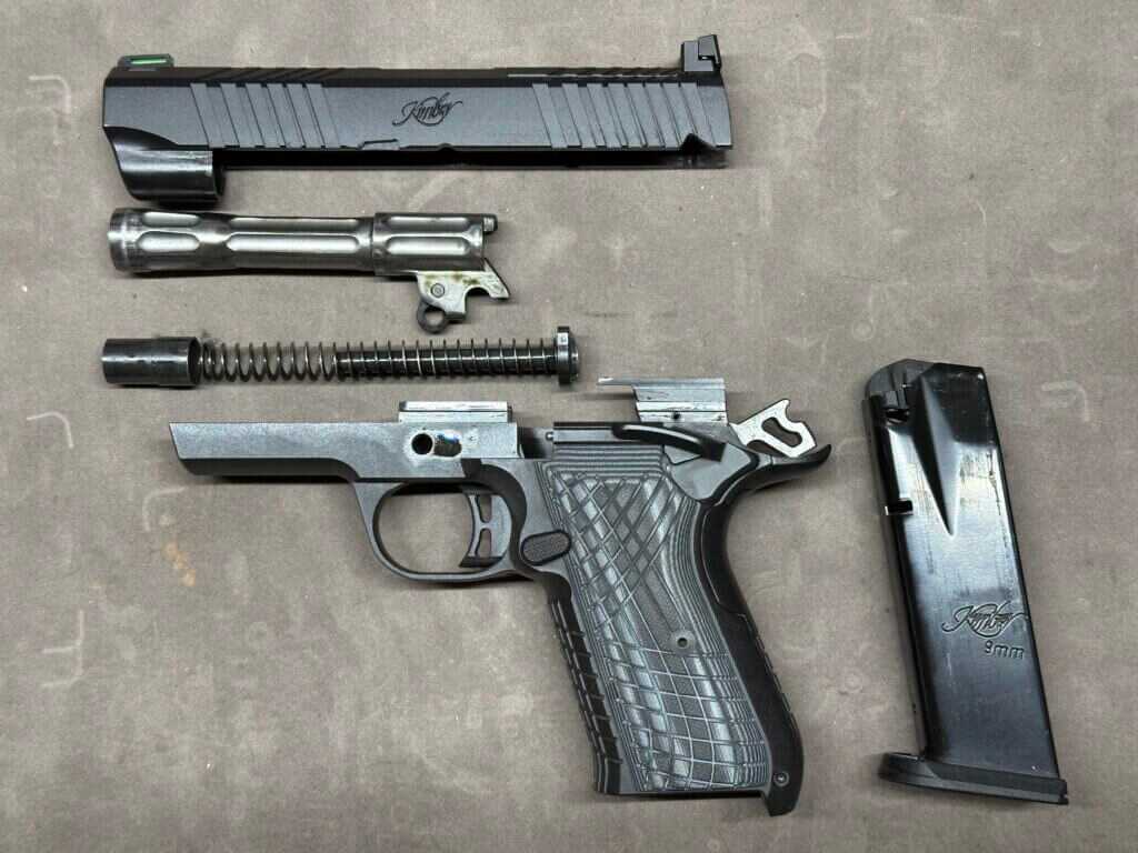 A disassembled gun is displayed on a grey velvet mat.