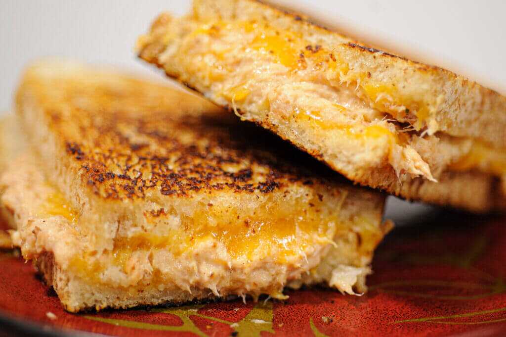 Crispy grilled fish sandwich with smoked trout and cream cheese, sliced and stacked for a juicy melt.