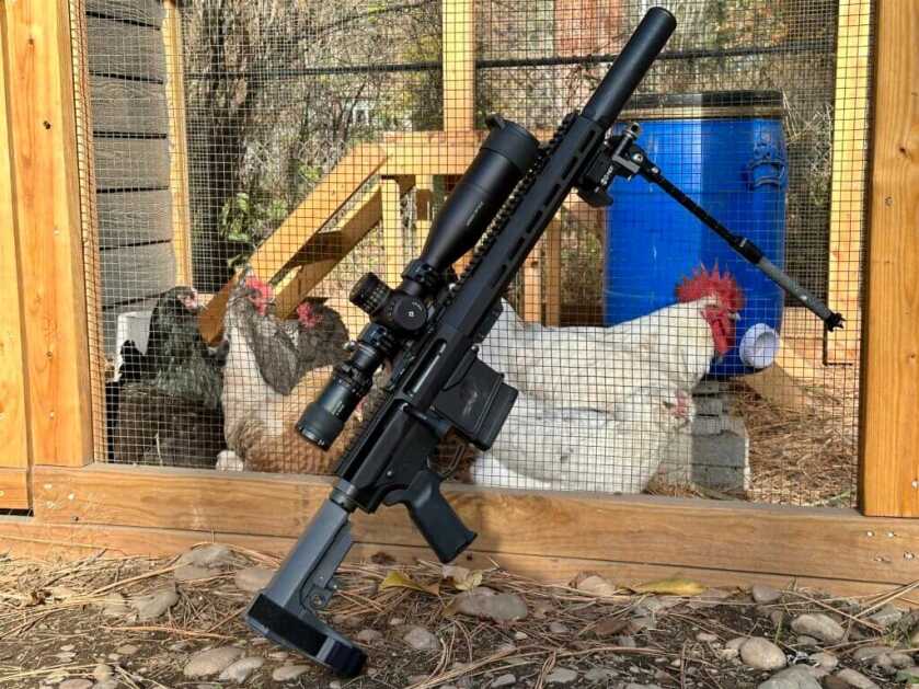 UP-10 8.6 Blackout suppressed rifle leaned on a chicken coop, field-ready setup.