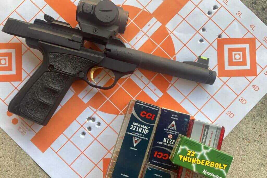 Browning Buck Mark .22 LR pistol with red dot sight on target sheet beside ammo.
