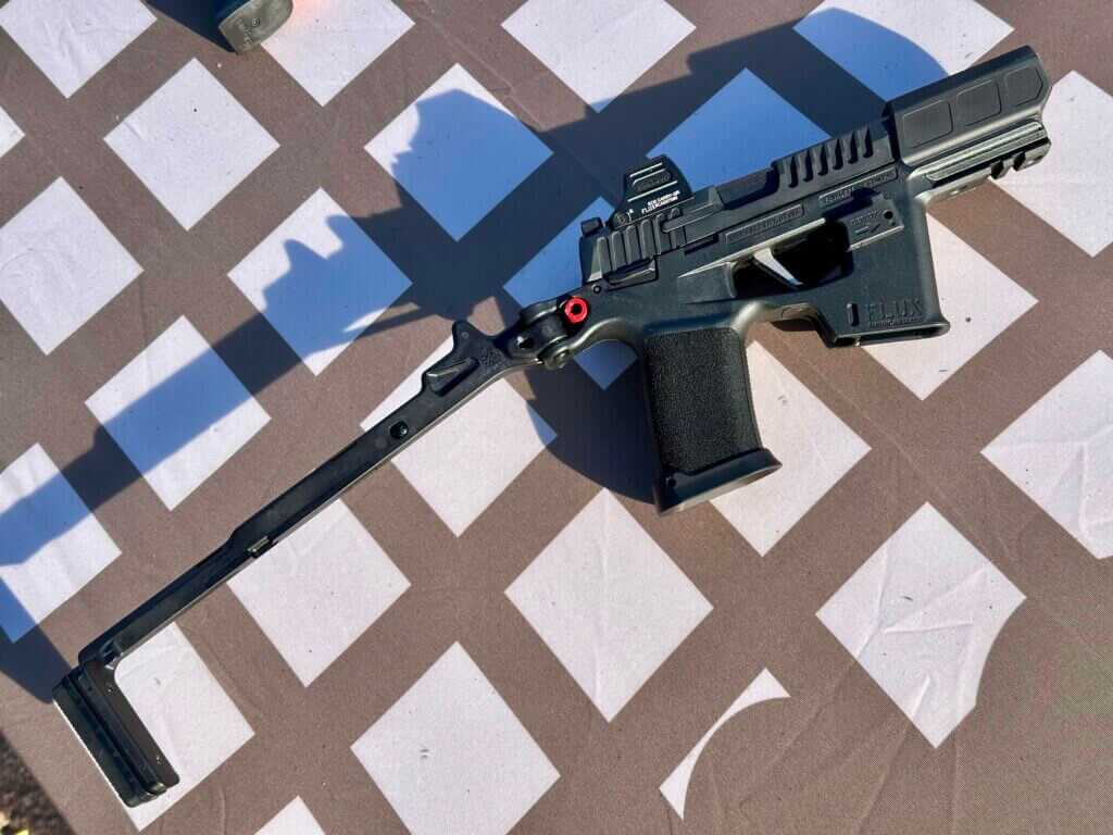 A black PDW with the stock extended lays on a brown and white table.