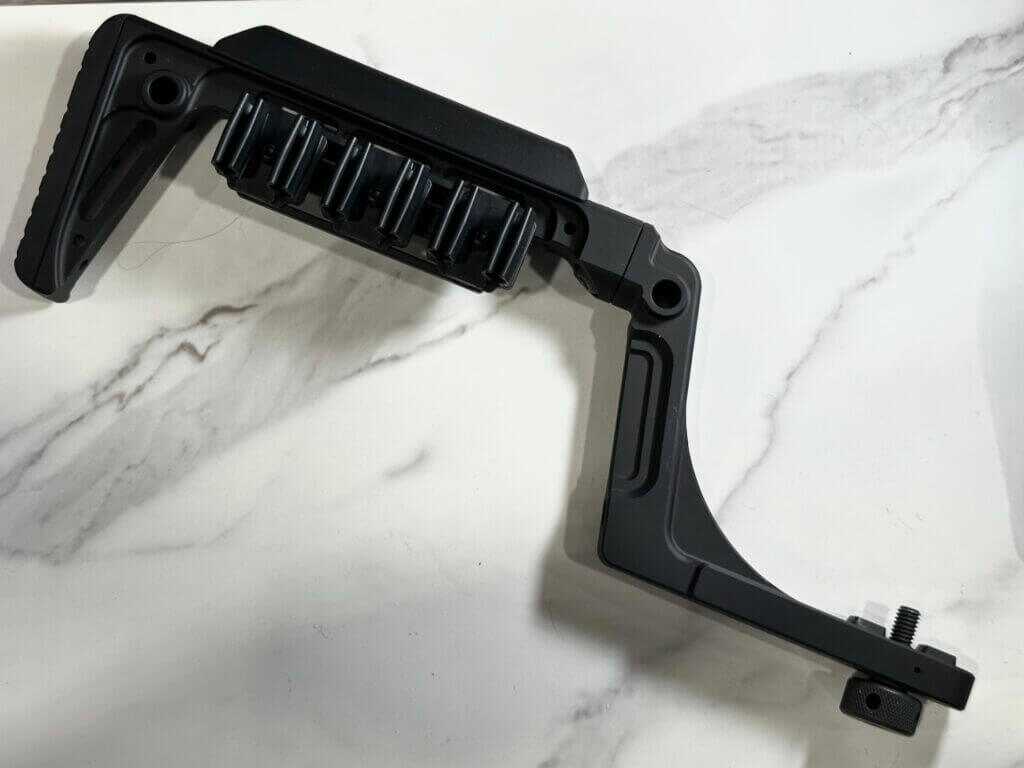 A black buttstock with a shell quiver on it lays on a white granite background.