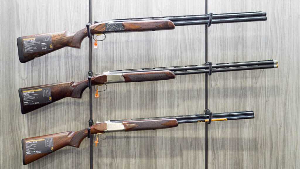 Three shotguns hanging on a wall rack.