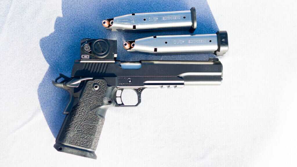 The gun laying on a table facing right with the right side up with two magazines arranged above in on the table.