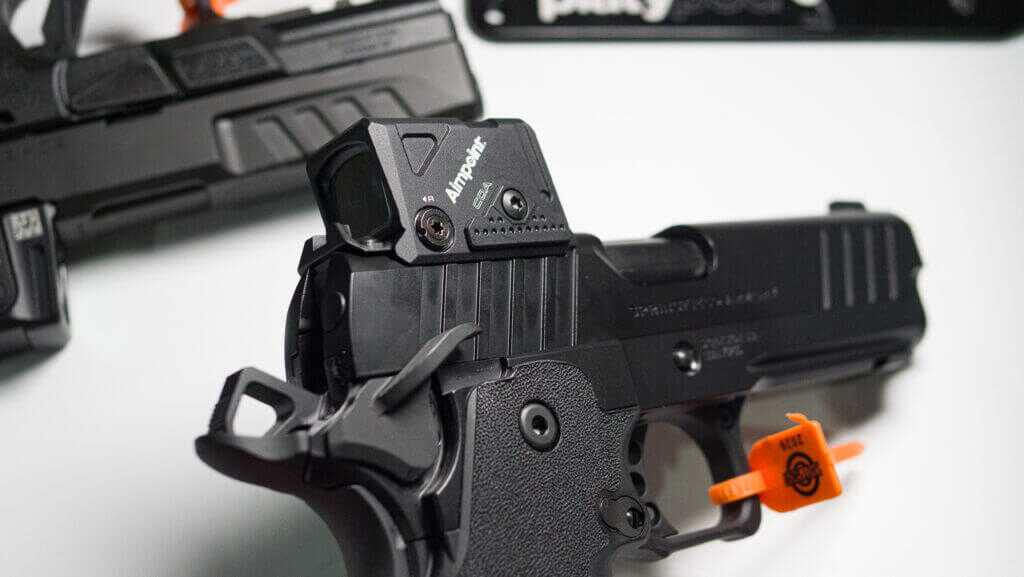 a Prodigy pistol pointing down at the table with the optic attached.