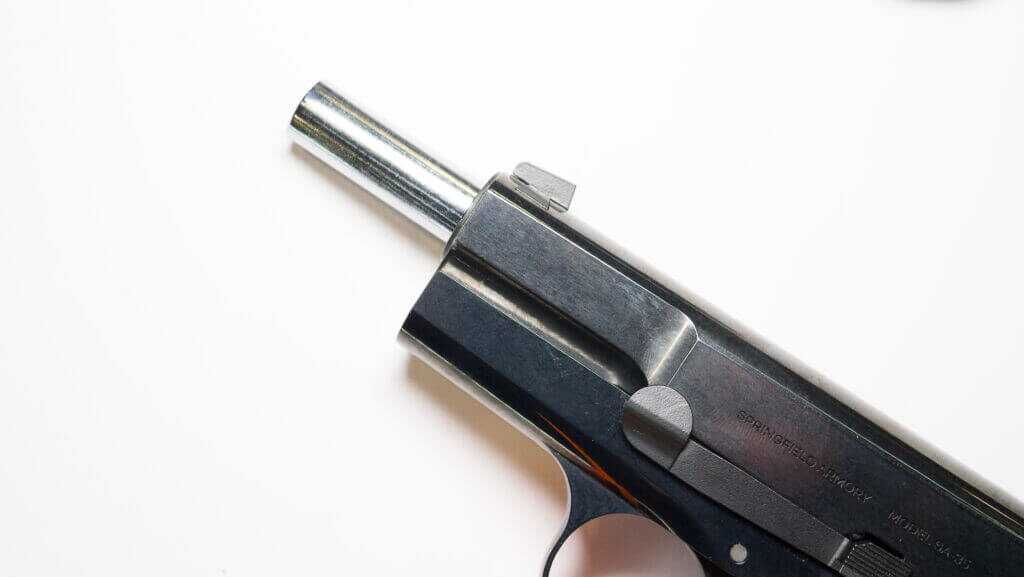 the stainless barrel protrudes from the front with the slide pulled back and gun on its left side facing left.