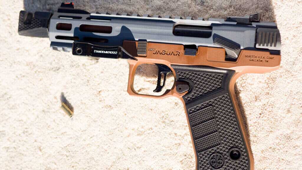 The whole gun lying on a table facing left with a spent .22 case nearby.