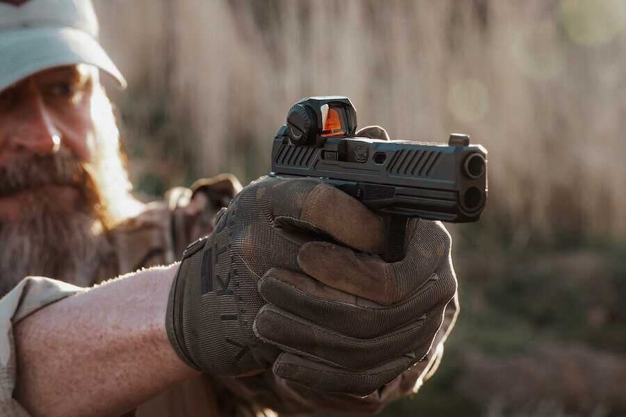 A man shooting a pistol with the Steiner MP5-C red dot on it.