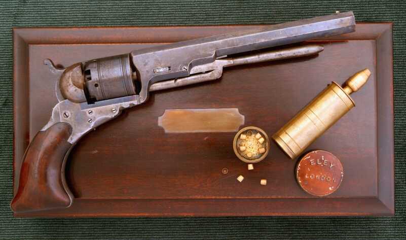 The No. 5 models were later fitted with loading levers which made it possible to reload without taking the gun apart. This cased example also has the later single nozzle power flask since the cylinder did not have to be removed to reload. 