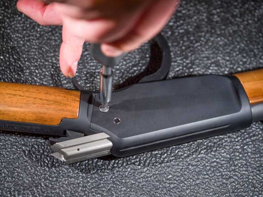 Close up of a hand using a screwdriver on the left side of the receiver. The is pointing to the right.