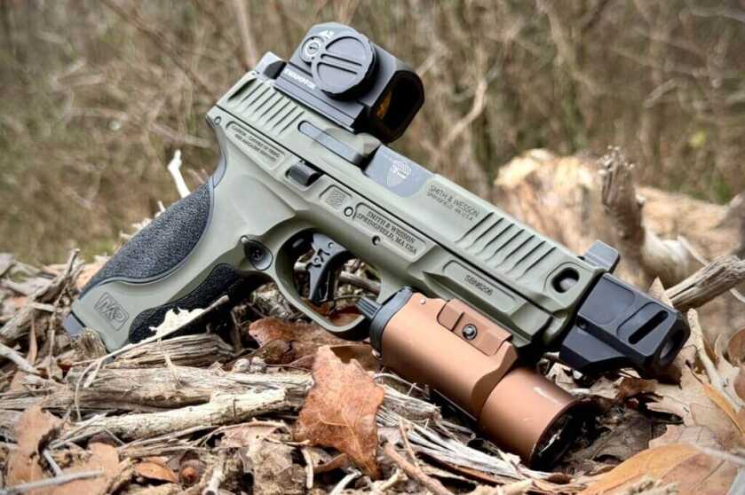 S&W Spec Series Metal M2.0 with handgun light resting on twigs and leaves outside