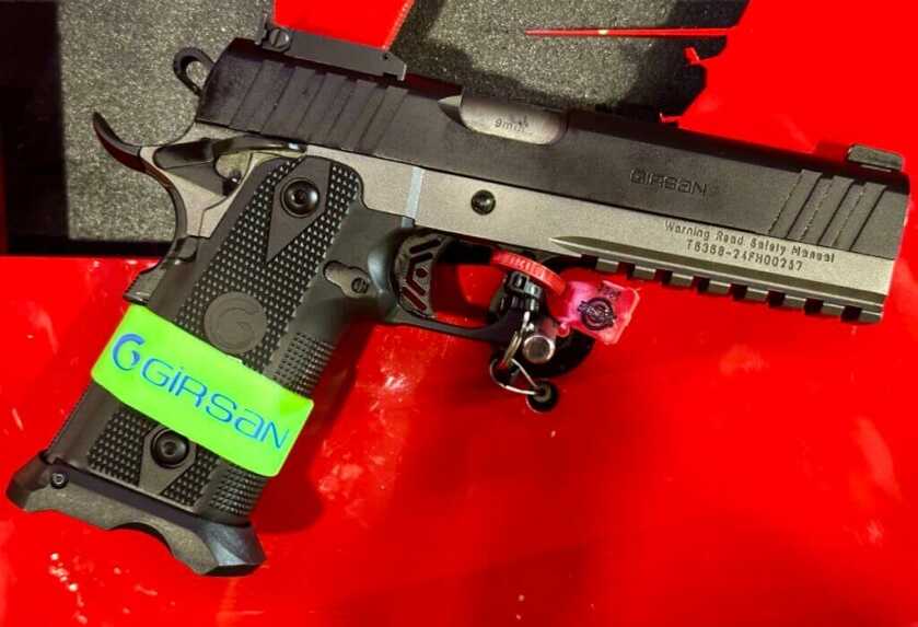 A silver and black handgun sits on a red background, pointed down and toward the right.