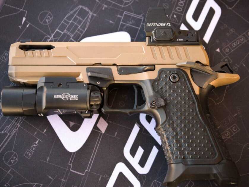 The gun laying on a table with a printed table cloth. the gun is facing left.