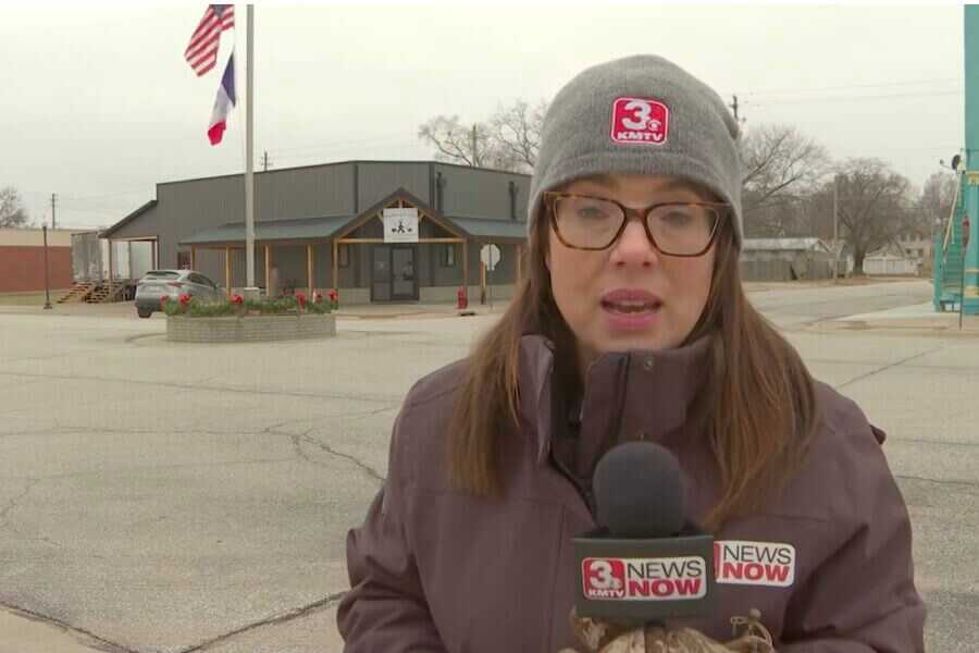 Female reporter in the front of a deer processing store.