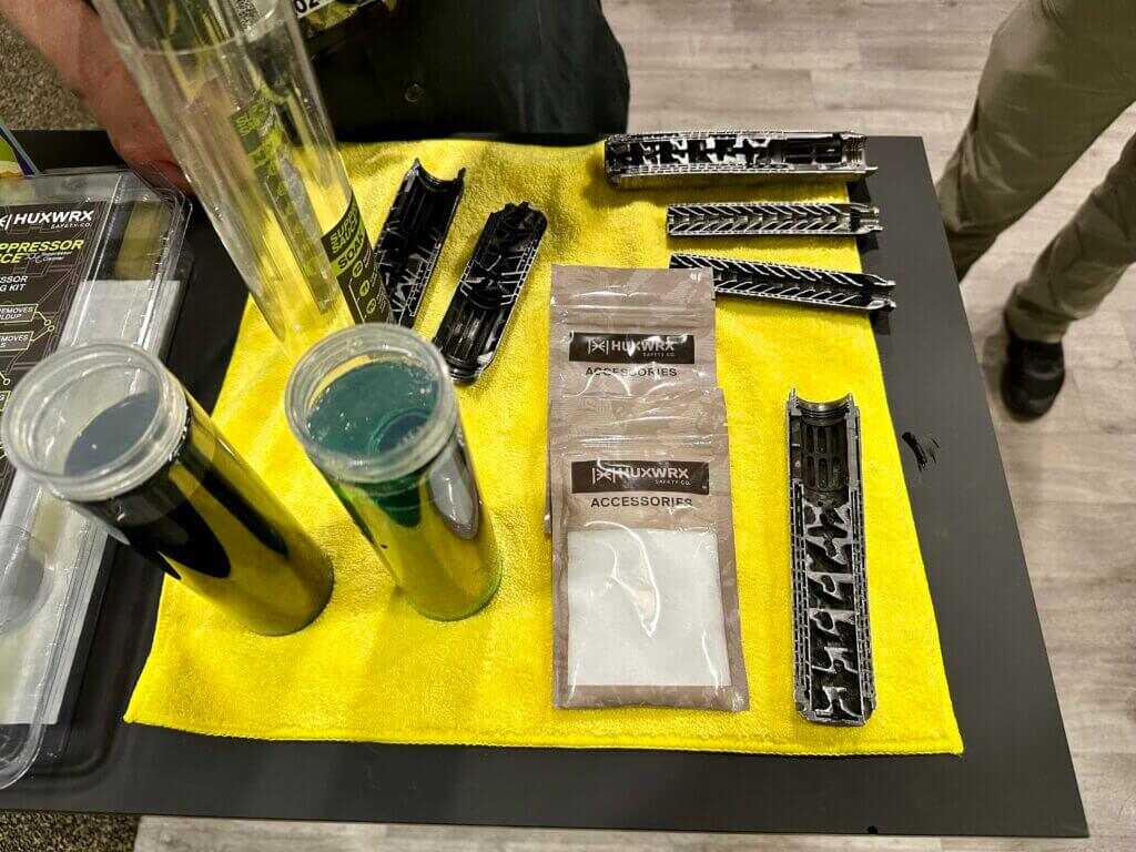 A bunch of different suppressors and cleaning products lay on a table.