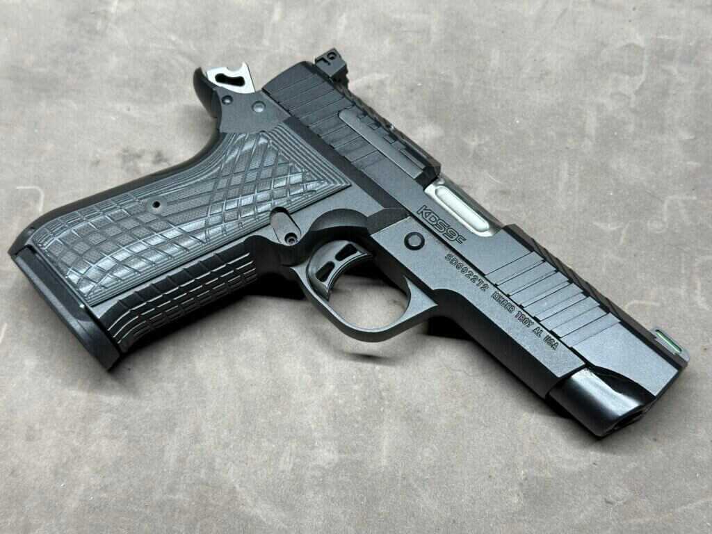 A handgun rests on a tan backdrop.