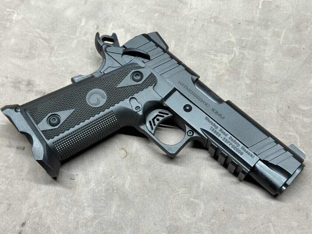 A black handgun is posed on a tan tabletop.