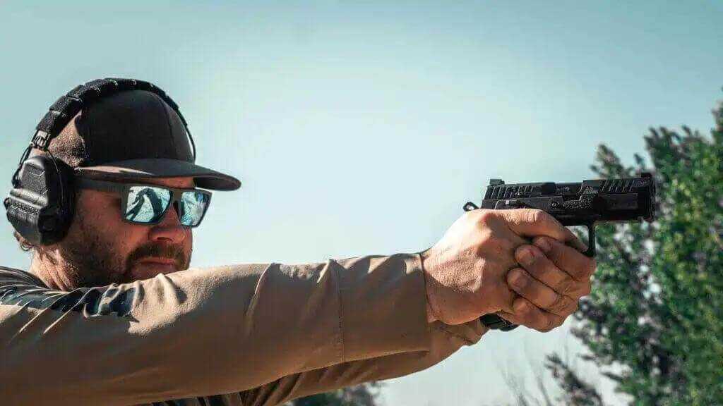 Man with reflective sunglasses shooting handgun