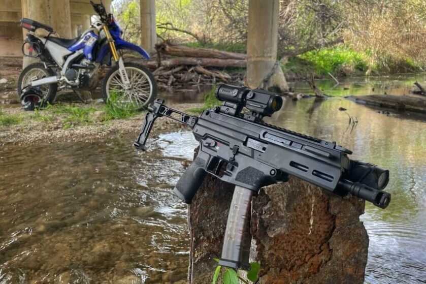 Rifle on rock next to creek under bridge