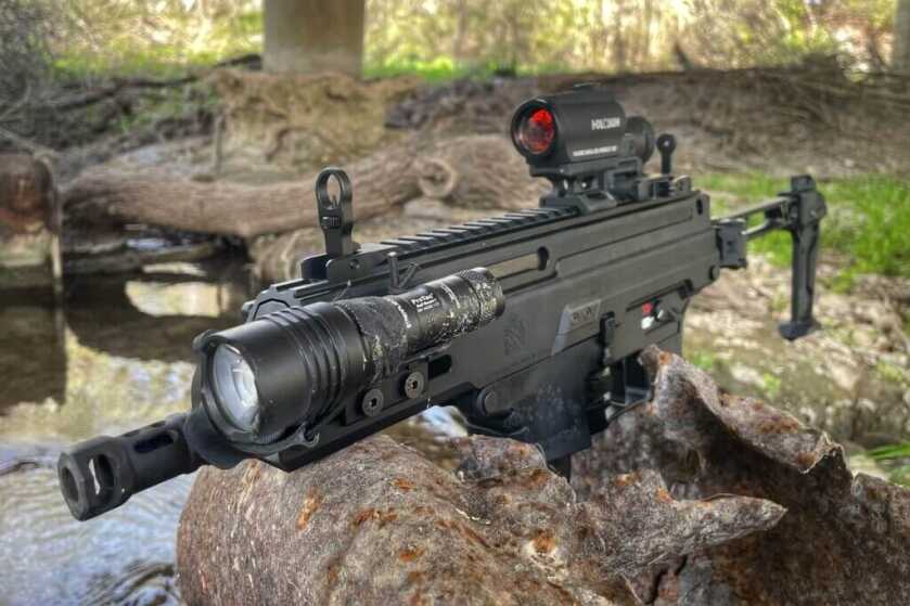 Kuna rifle propped on rock with focus on iron sights