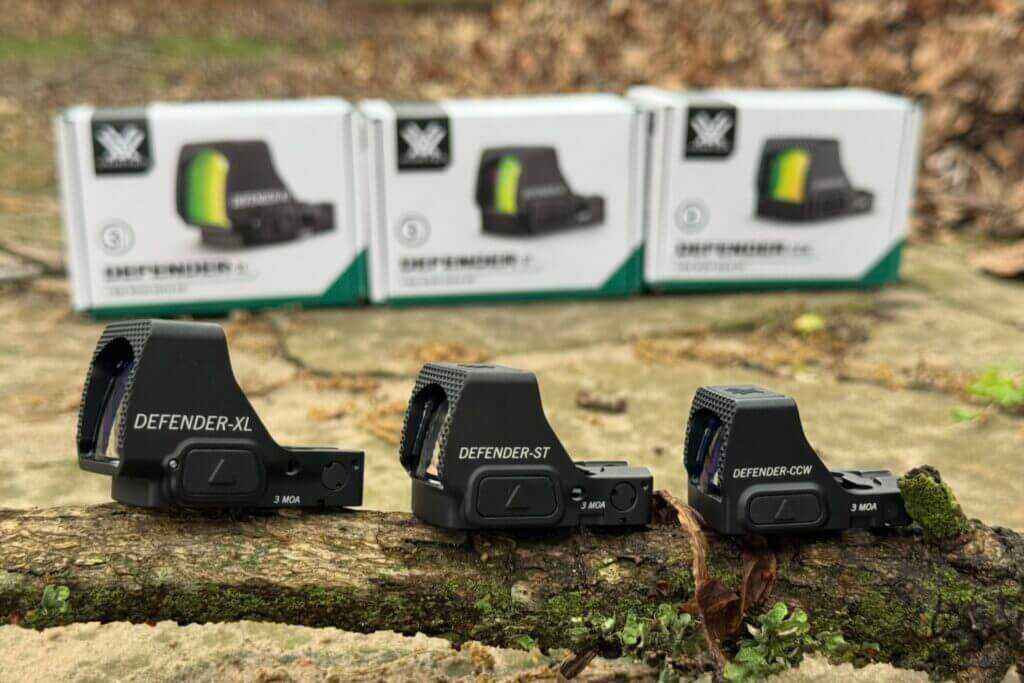 Vortex Defender Series green dot optics lined up on tree branch in front of boxes