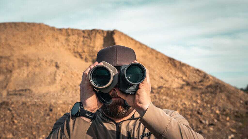 man holding two spotting scopes