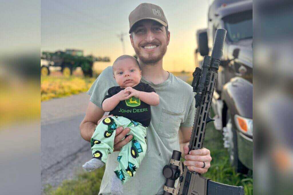 man holding a baby and a rifle Father’s Day shooters
