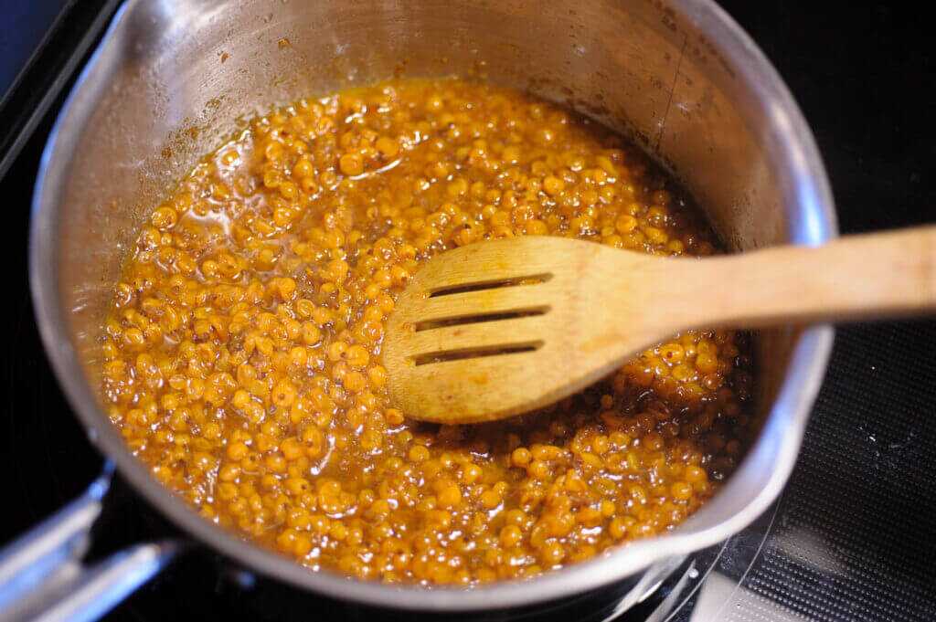 berries in a saucepan with a wooden spoon.