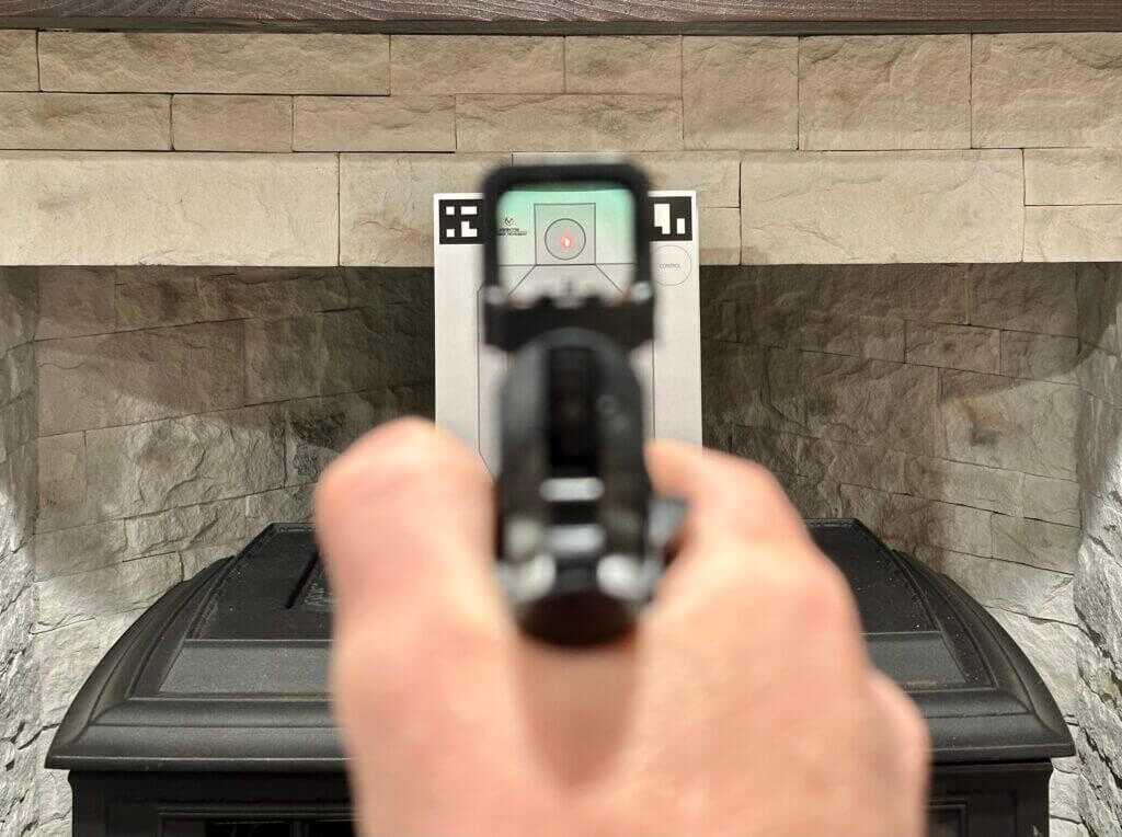 looking through a red dot sight at a target indoors. MAX