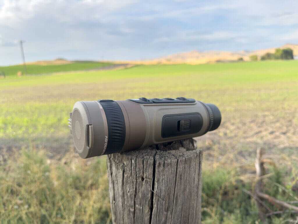 Side view of SIG Echo MV50-DV handheld thermal monocular with eyepiece and port cover on a fencepost