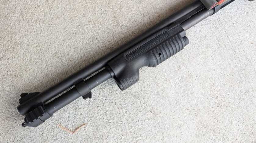 Pump shotgun with integrated forend light showing control placement