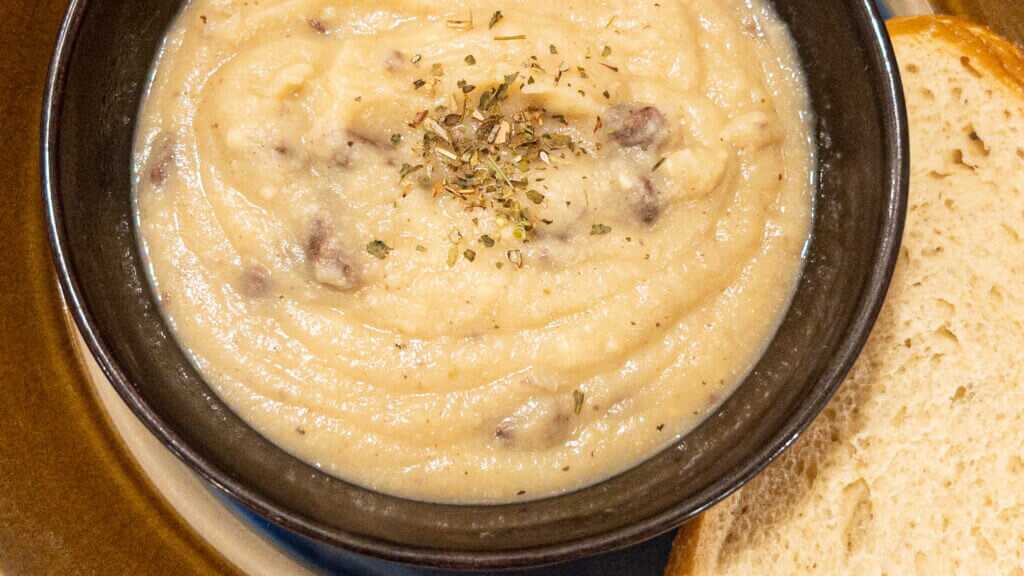 Close up photo from straight above os soup in a bowl on a plate with bread on the side.