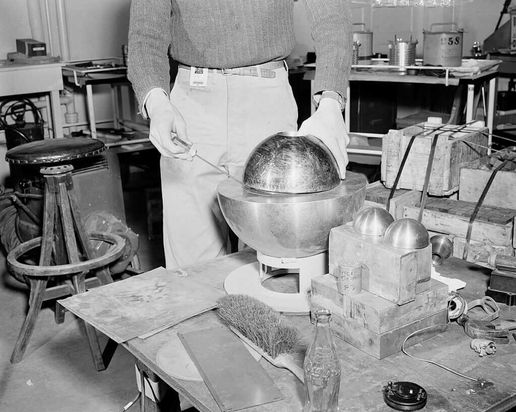 Beryllium neutron reflector hemispheres positioned over plutonium sphere during criticality experiment at Los Alamos