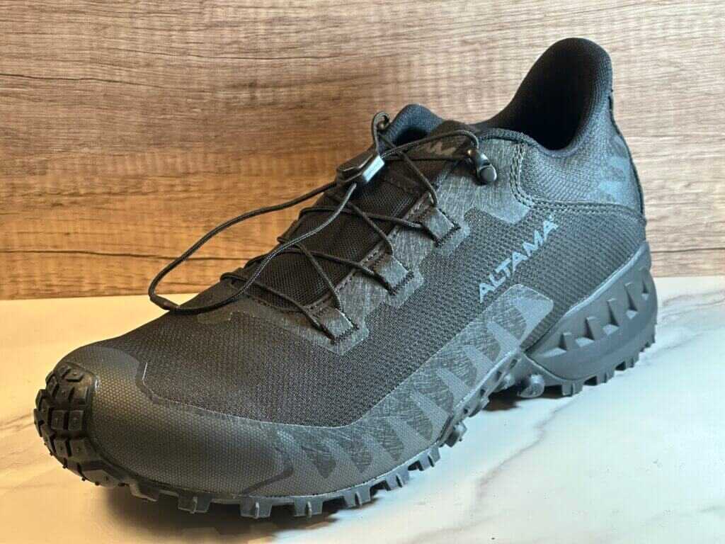 A black shoe is posed on a white floor.