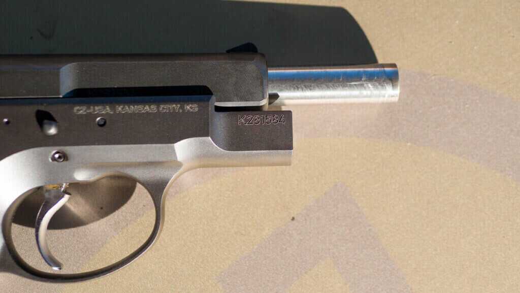 The front of the gun with the gun facing right. Closeup view of the slide retracted exposing the end of the barrel.