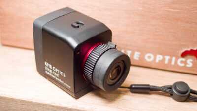 close up view of the monocular sitting on a wood shelf, showing the objective lens.