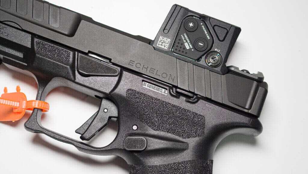 Close up view of an Eschelon pistol lying on a table with a COA sight attached. The gun isfacing left.