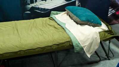 The top portion of the bedrool sitting on a cot with the top zipped closed.