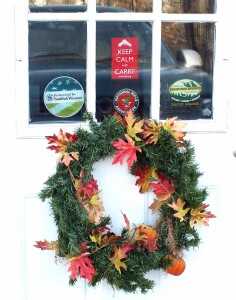 There's no problem with indicating you're a gun owner, but a "Trespassers will be Violated" or "Go Ahead, Make my Day" sign will almost certainly become an issue in a use of deadly force civil case.