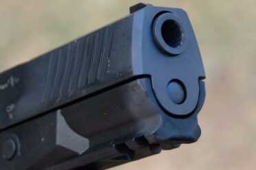 The frame has an integral Picatinny rail, and the slide has forward cocking serrations.