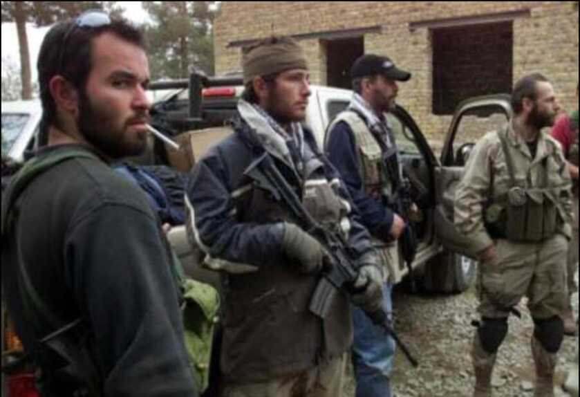military guys standing around outside a brick building with rifles