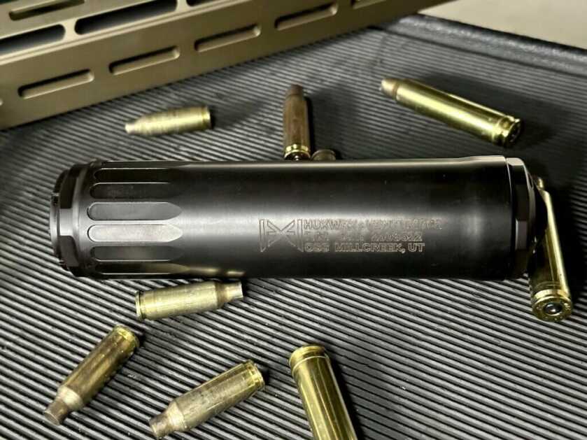 Black Ventum 762 suppressor sits among rifle brass on a table.