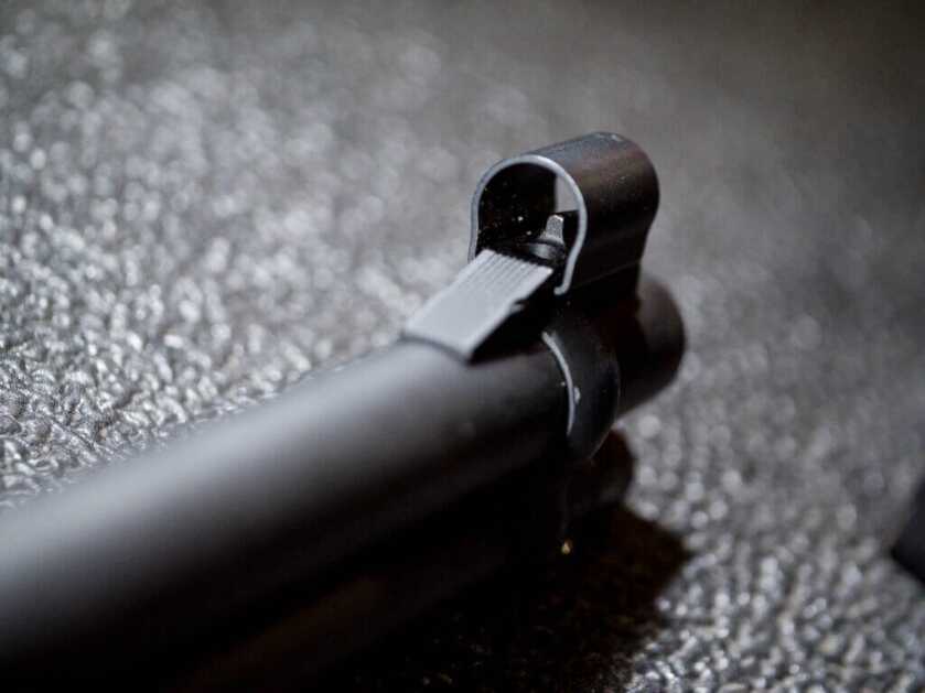 Close up of the end of the barrel with the hooded front sight. THe gun is pointed away and right.
