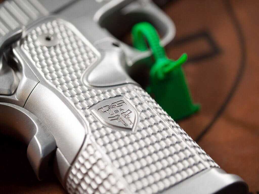 Close up view of the right side of the grip showing the machined stippling and Cabot Guns crest. the gun is pointing to the right.