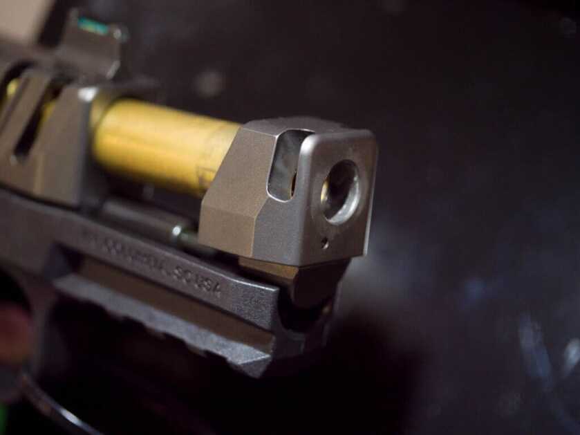 Close up view of the end of the barrel. the slide s open and the titatnium nitride finished barrel is exposed. The gun is pointed towards and to the right.