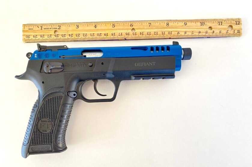 A Tangfolio rimfire pistol next to a wooden ruler