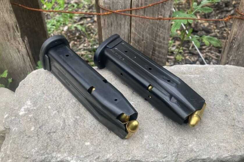 Two magazines loaded with 9mm ammo sitting on grey rock