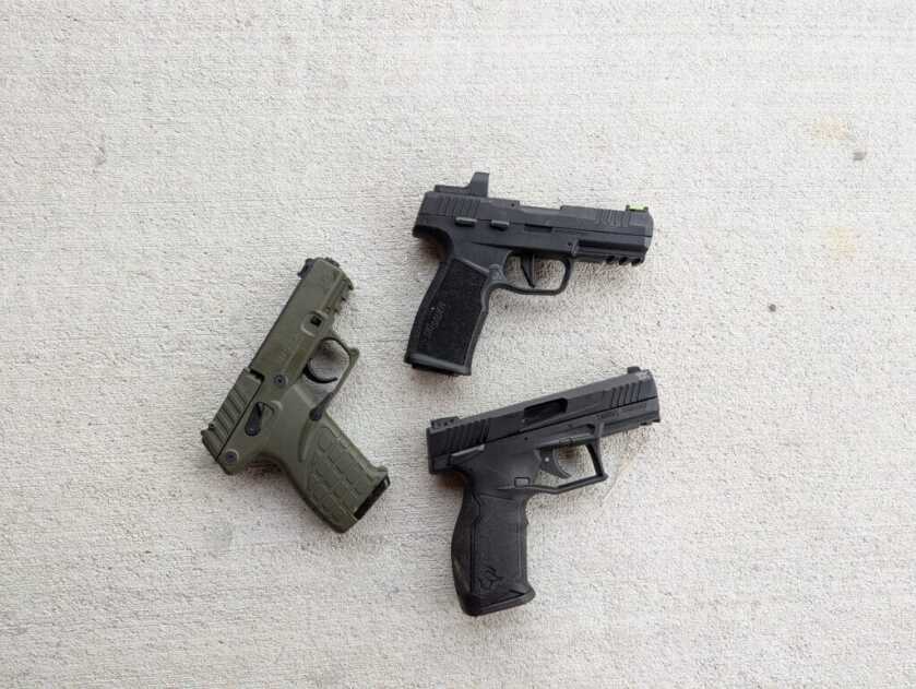 Three modern rimfire pistols on concrete