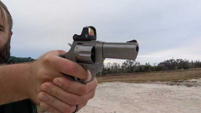 man aiming with a red dot ready revolver